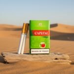 ซองบุหรี่ Capital Double Apple สีเขียวและมวนบุหรี่ วางบนขอนไม้แห้งในทะเลทราย แสงแดดอุ่นช่วงเย็น