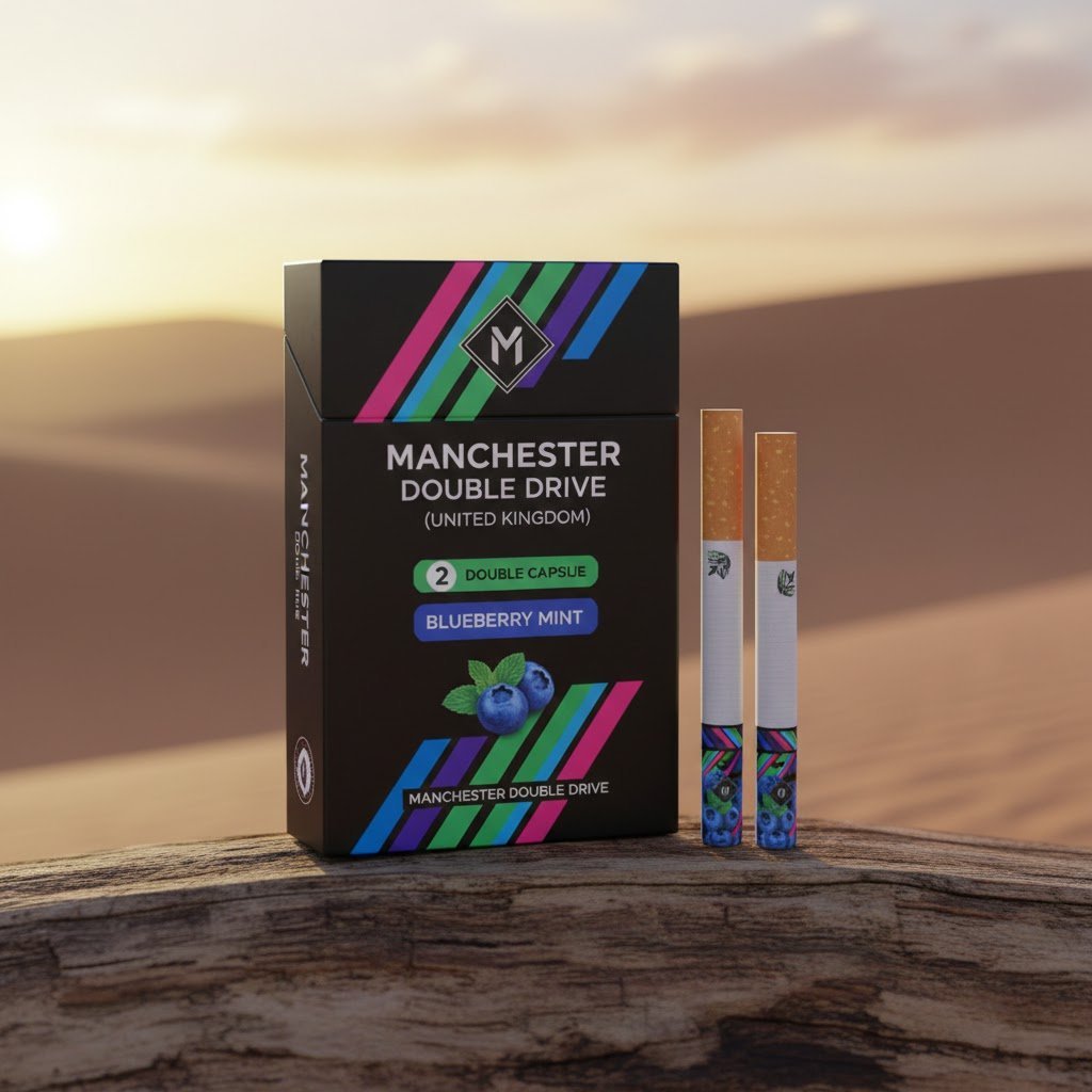 บุหรี่ Manchester Double Drive ซองสีดำลายทางหลากสี พร้อมเม็ดบีบคู่บลูเบอร์รี่และมิ้นต์ วางบนขอนไม้ในทะเลทราย