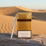 ซองบุหรี่ ESSE Special Gold สีทองแบบ Super Slim วางบนขอนไม้ท่ามกลางทะเลทรายสีทอง