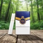 กล่องบุหรี่ 555 State Express Gold Pearl สีน้ำเงินทอง วางบนโต๊ะไม้ในบรรยากาศป่าธรรมชาติ