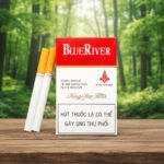 กล่องบุหรี่ Blue River Red สีขาวคาดแดงดีไซน์คลาสสิก วางบนโต๊ะไม้ฉากหลังป่าไม้สีเขียวขจี